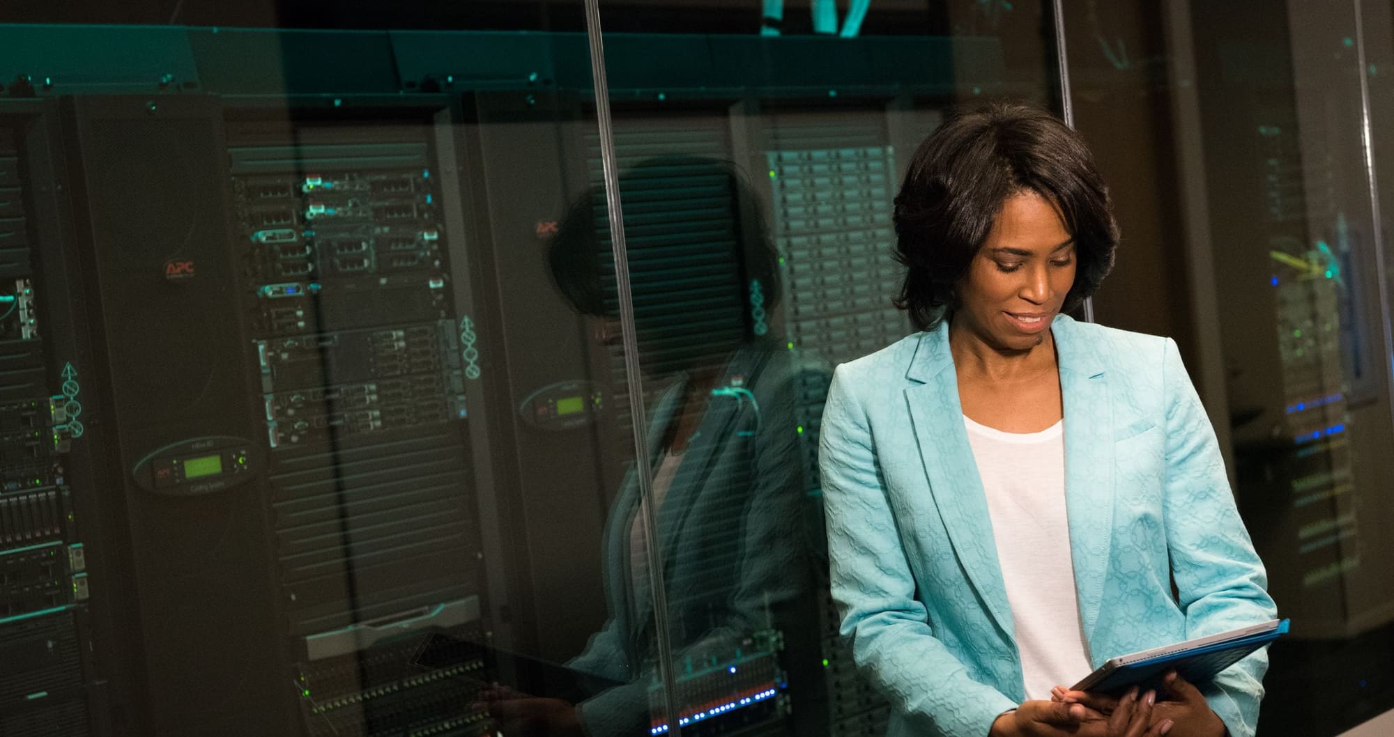 A technician holding a tablet beside server racks in a data centre